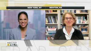 Soledad in light blue jacket talking remotely to Juliet Schor who is sitting in front of a bookshelf