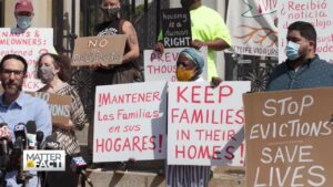 people holding signs in English and in Spanish that protest evictions